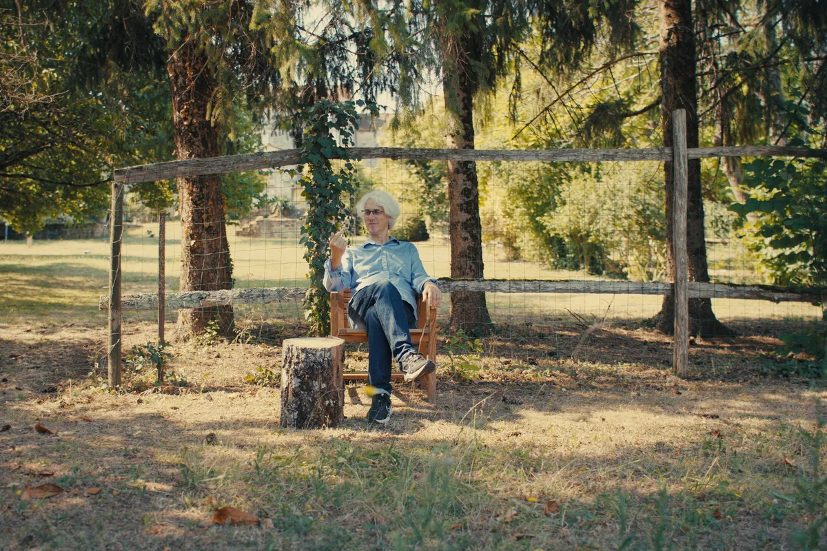 José Le Roy assis dans un parc, détendu, dans la lumière du matin